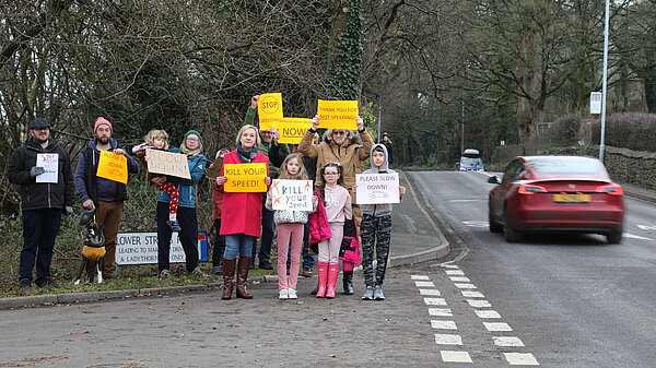 Campaigners holding up signs to encourage motorists to slow down